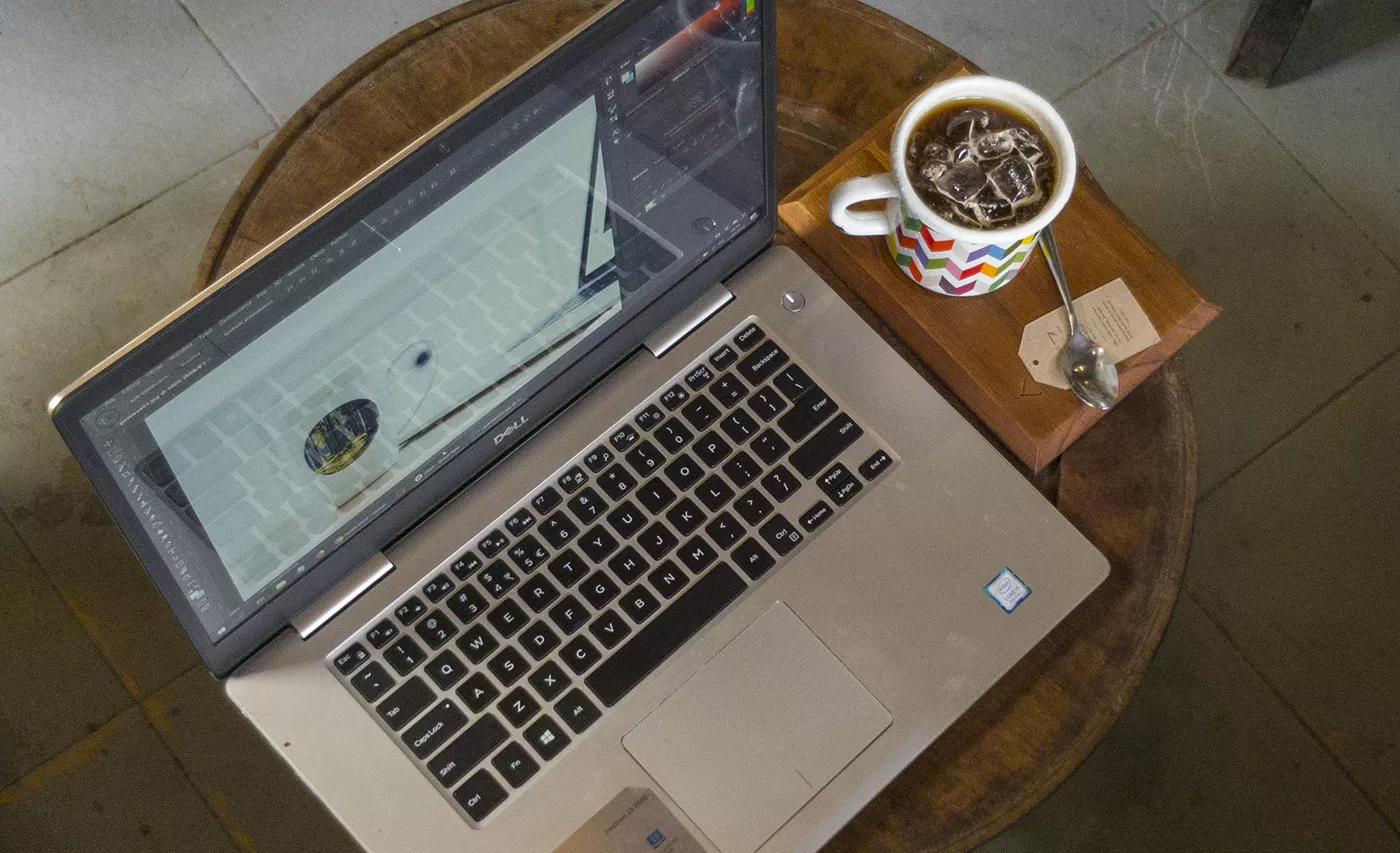 Laptop z projektem graficznym i kawa na drewnianym stoliku