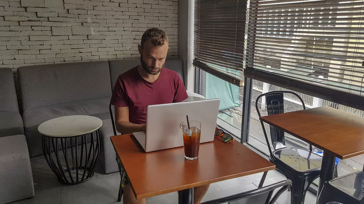 Mężczyzna pracujący zdalnie na laptopie w kawiarni