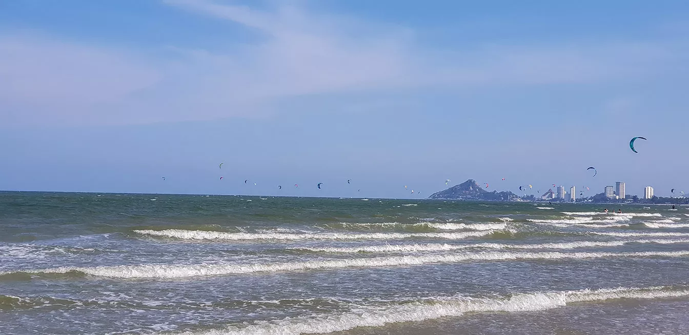 Plaża z falami i kitesurferami w oddali